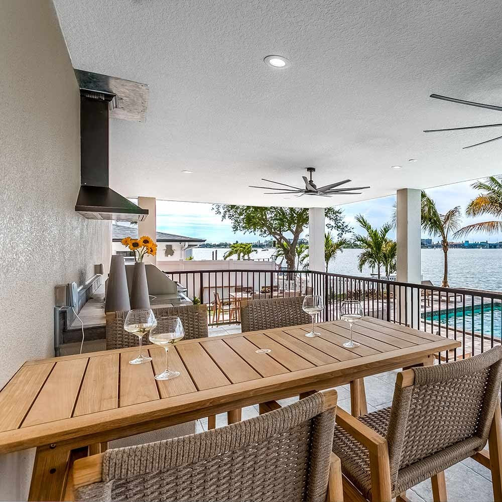 Teak outdoor counter-height dining table with matching woven chairs, light wood frames