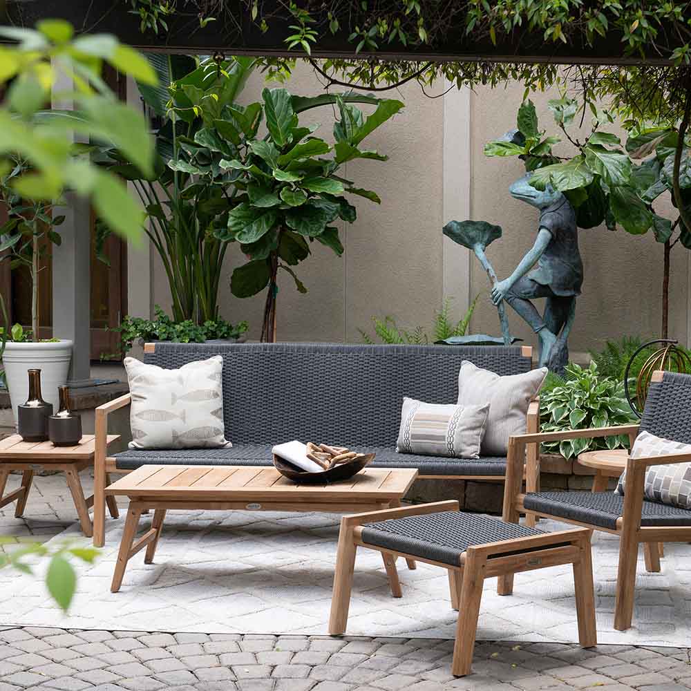 Outdoor bench seating set with gray cushions, two armchairs, and matching ottoman