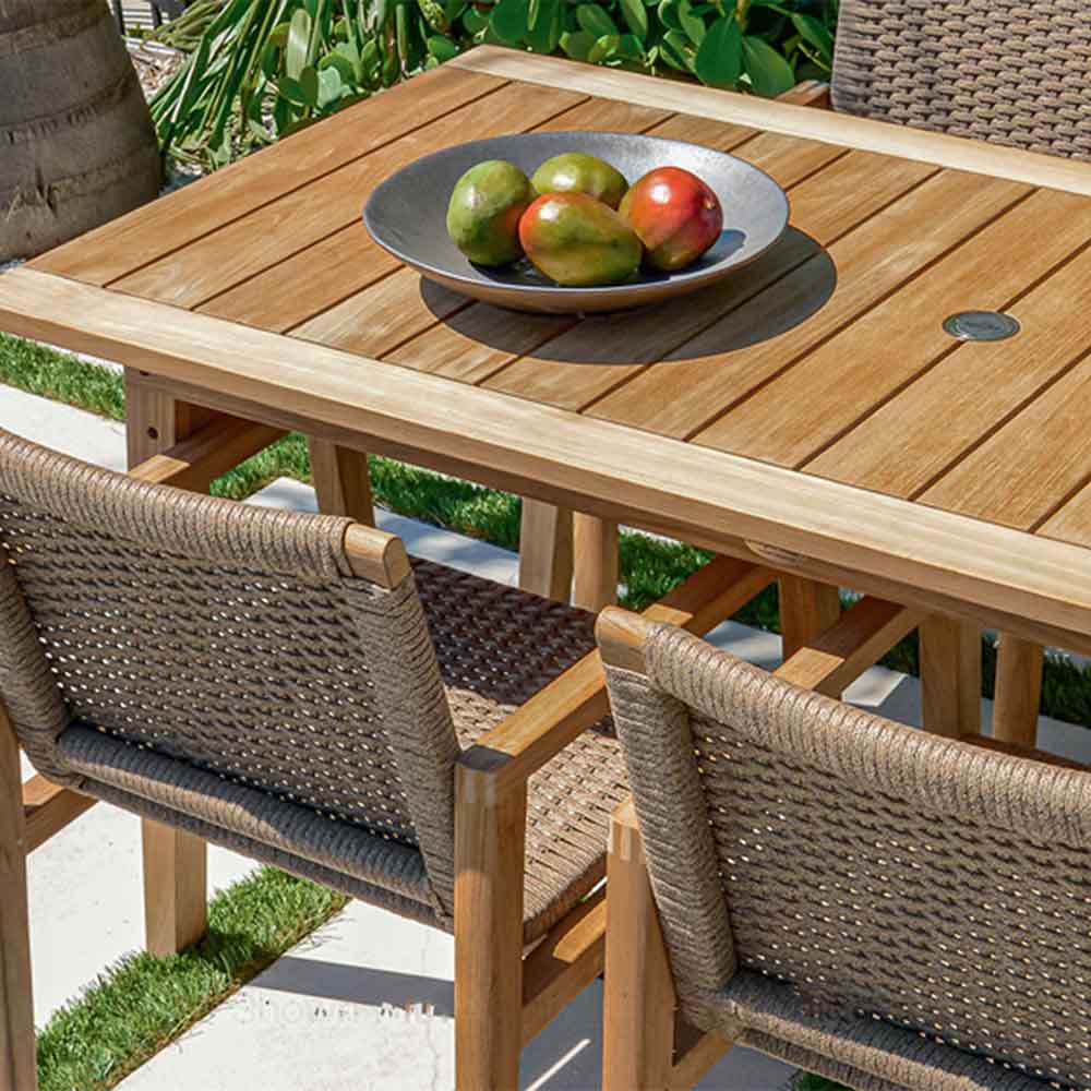 Outdoor dining table with natural wood slats and woven chair backs, fruit on top