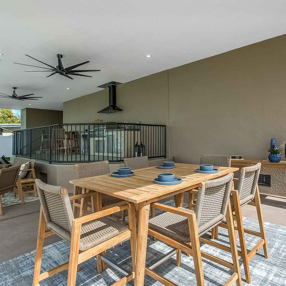 Outdoor dining table set on patio with woven-back chairs and natural wood tabletop