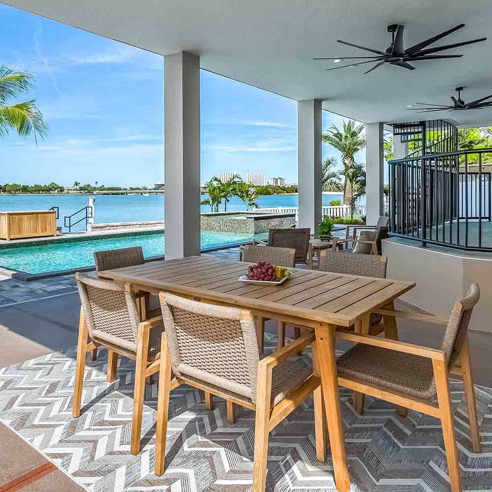Outdoor dining table with four woven-back chairs on covered patio