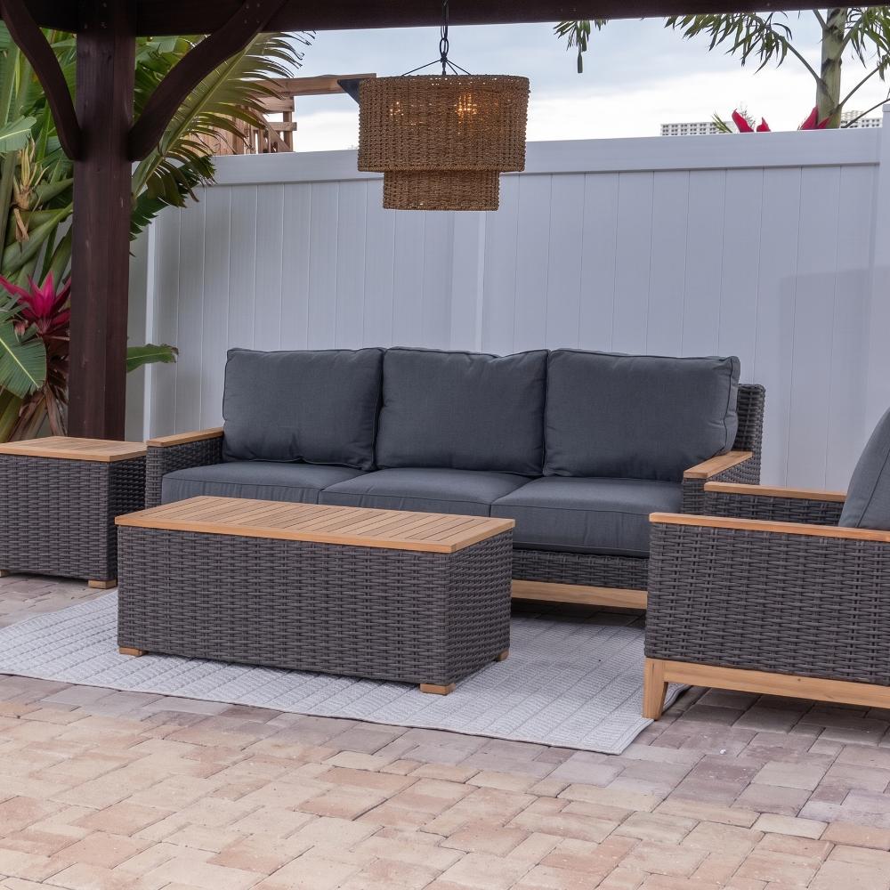 Outdoor patio furniture set with dark wicker sofa, armchairs, and two coffee tables with wood tops