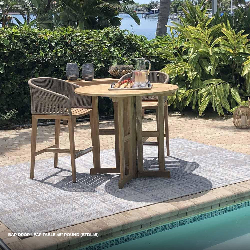 Round teak bar table with slatted top and drop-leaf seam, natural finish and sturdy legs.