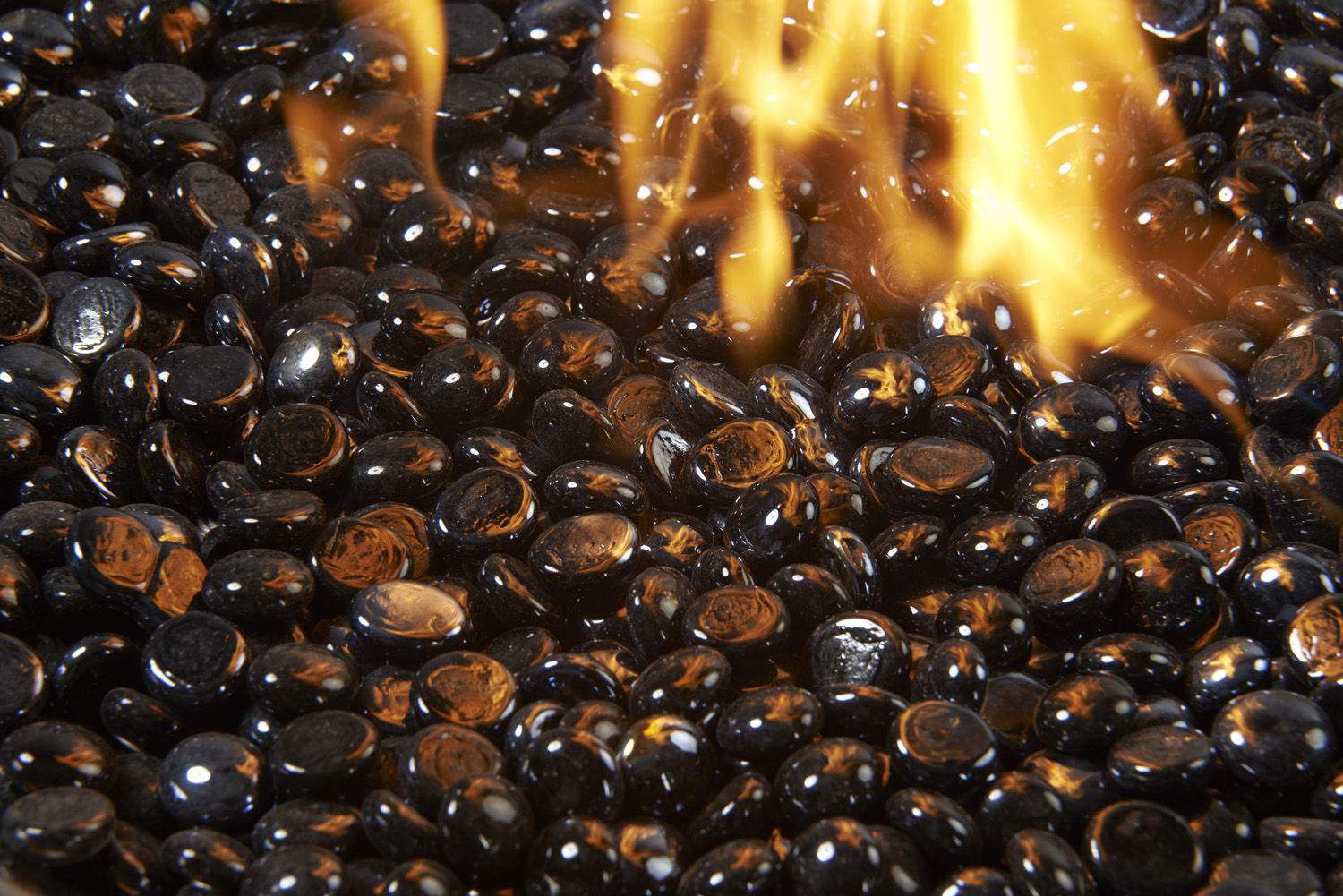 Flame-lit onyx fire glass gems, glossy black oval crystals