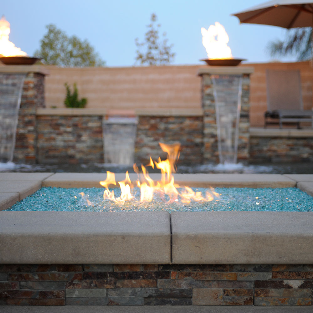 Blue glass fire media bed in a fire pit with visible flames