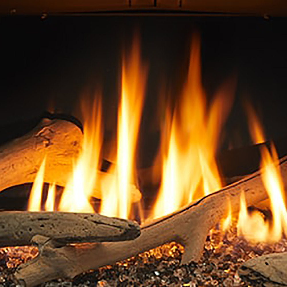 Driftwood log set with burning flames and stacked firewood logs