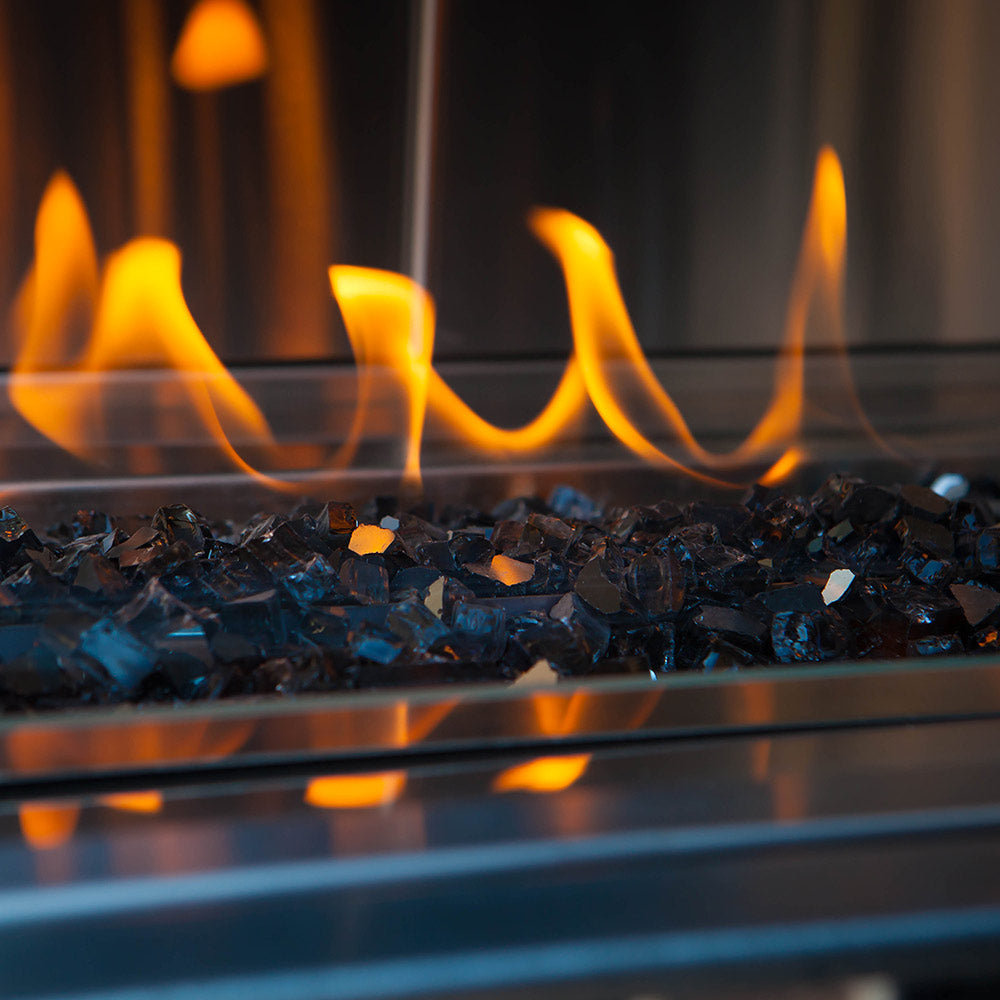 Gas fire pit burner bed with glowing coals and tall orange flames