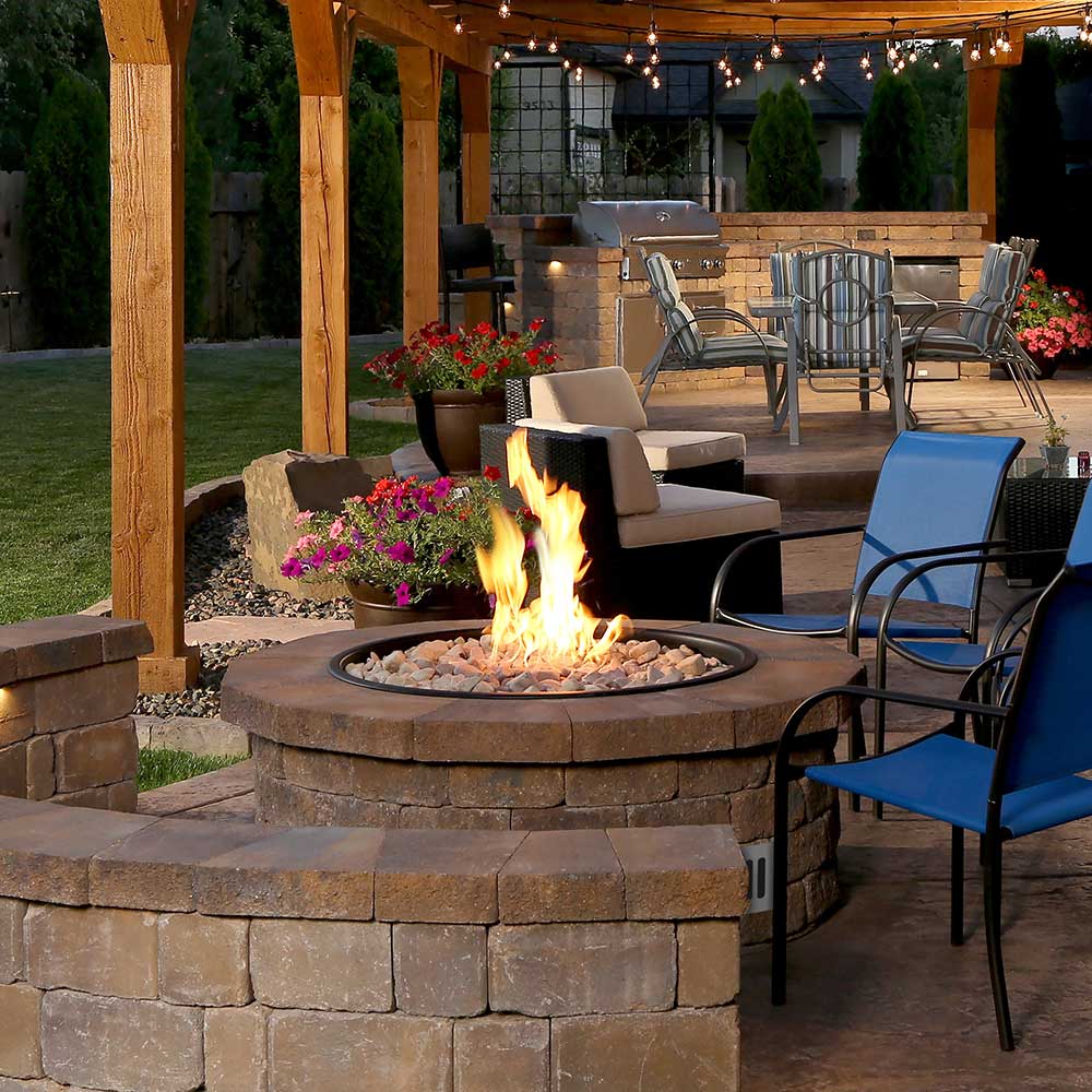 Brass gas fire pit with visible flame burning in round burner basin