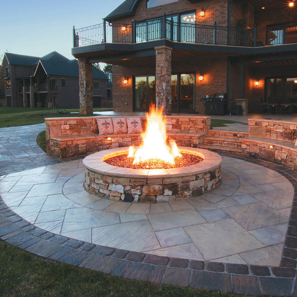 Round gas fire pit burner with bright flame in stone ring