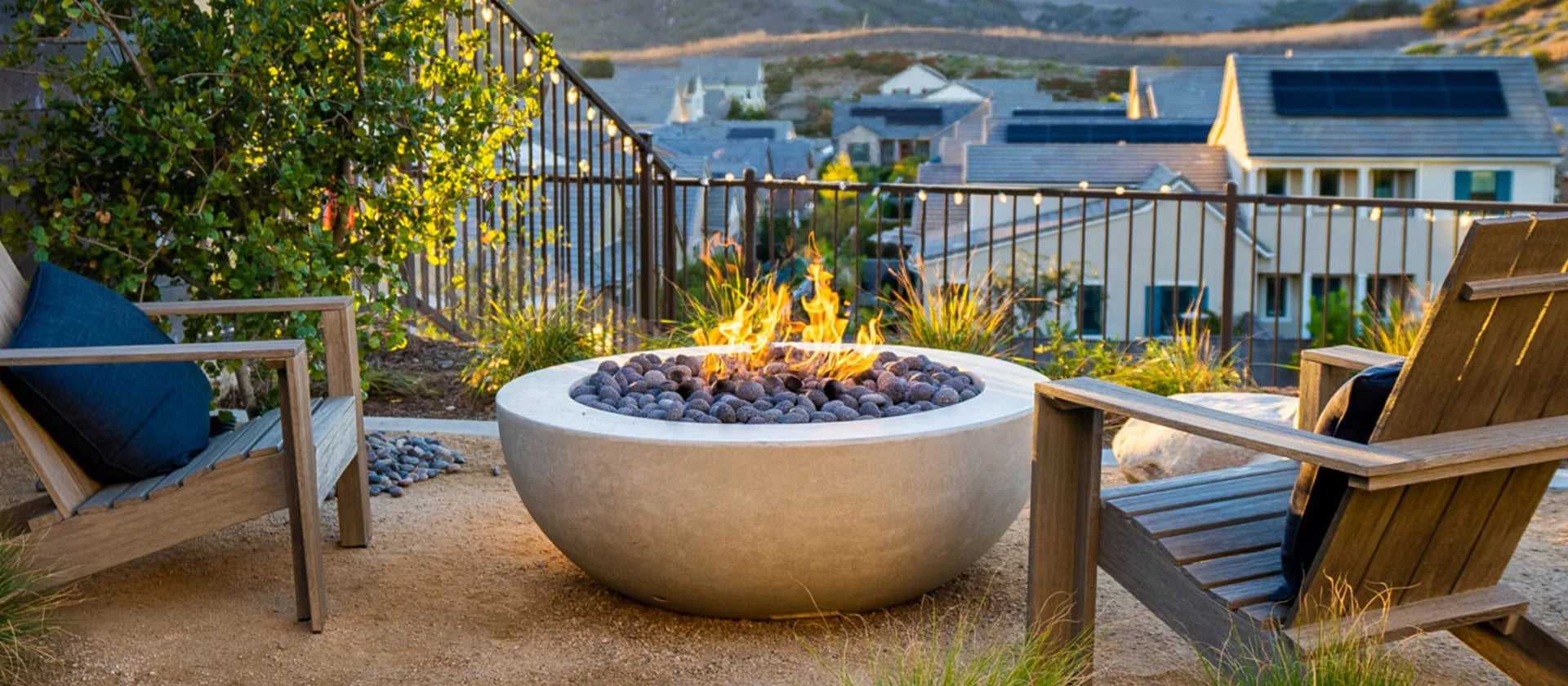 concrete fire pit with flame alit in a backyard during sunset