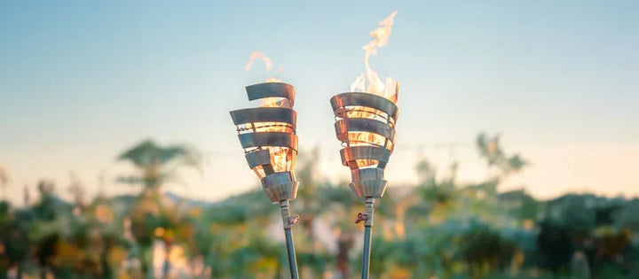 stainless steel gas torches lit aflame at sunset