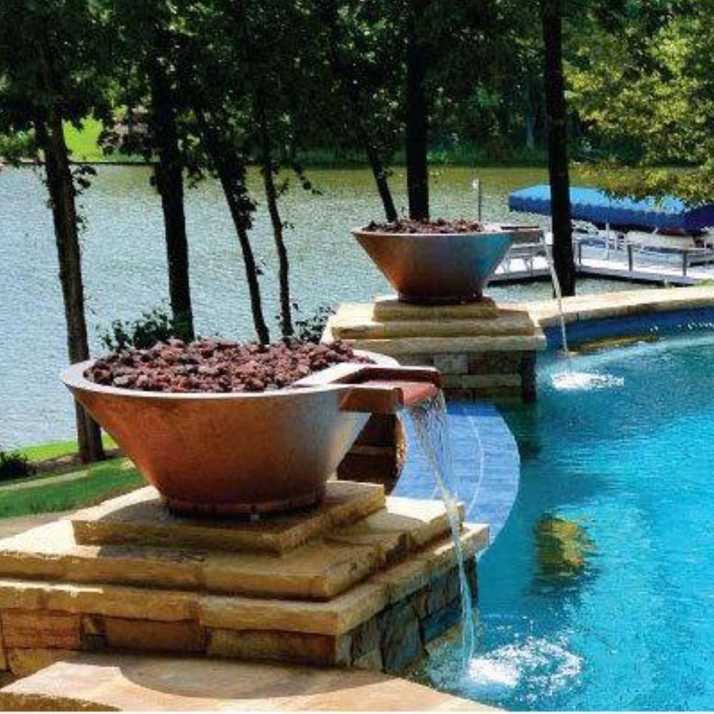 Outdoor copper round gas fire bowl on stone base by swimming pool