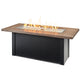 Linear gas fire table with wood-look top and black base, flames in the clear burner tray