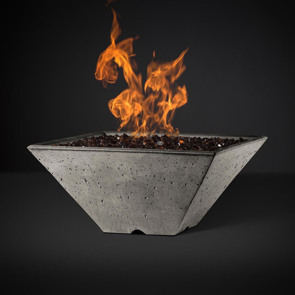 Square fire pit with burning flames, light gray speckled bowl with dark rocks