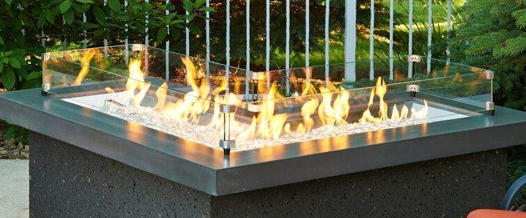 L-shaped glass wind guard for outdoor fire burner with clear glass panels and flames