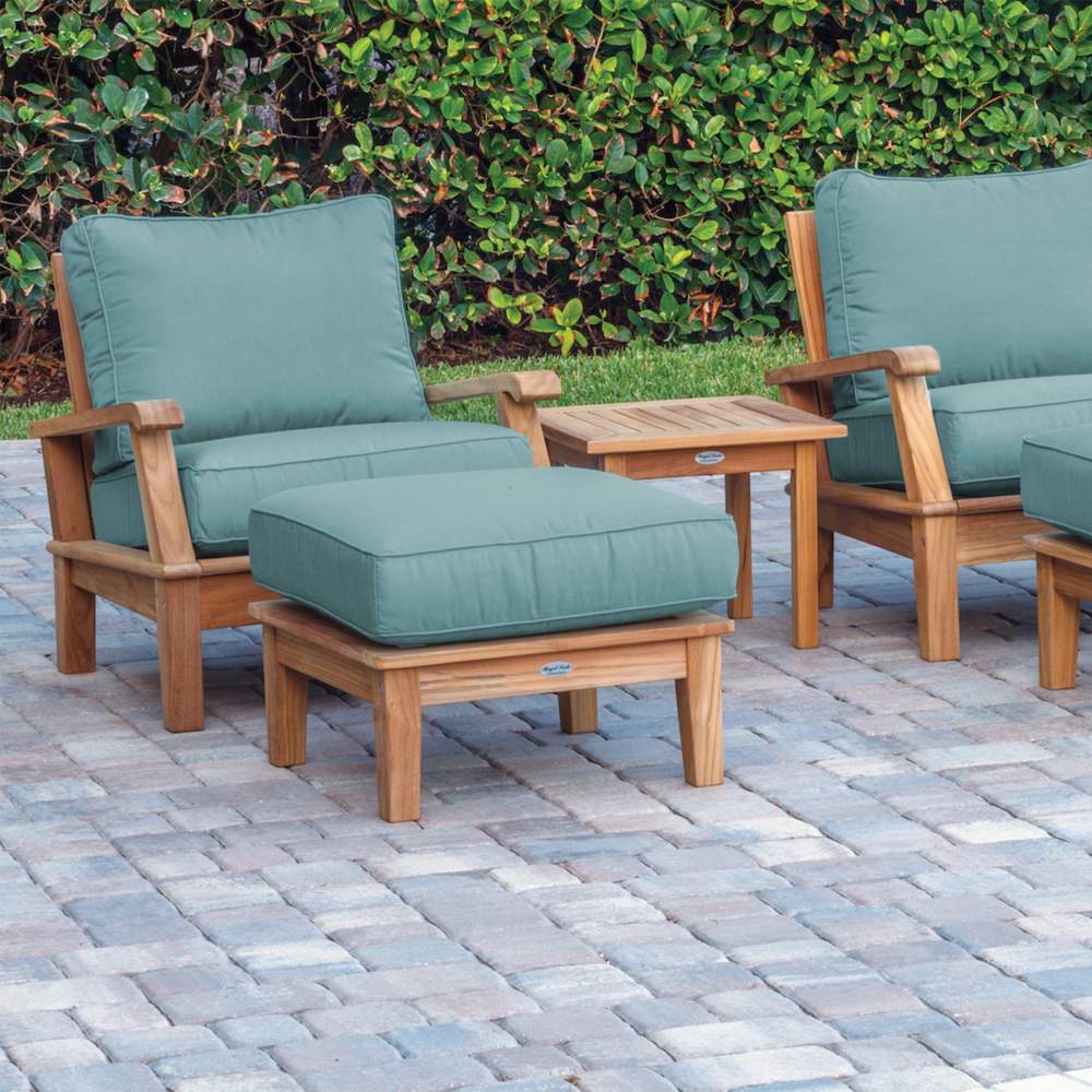 Teak outdoor lounge set with teal cushions, ottoman, and rectangular coffee table