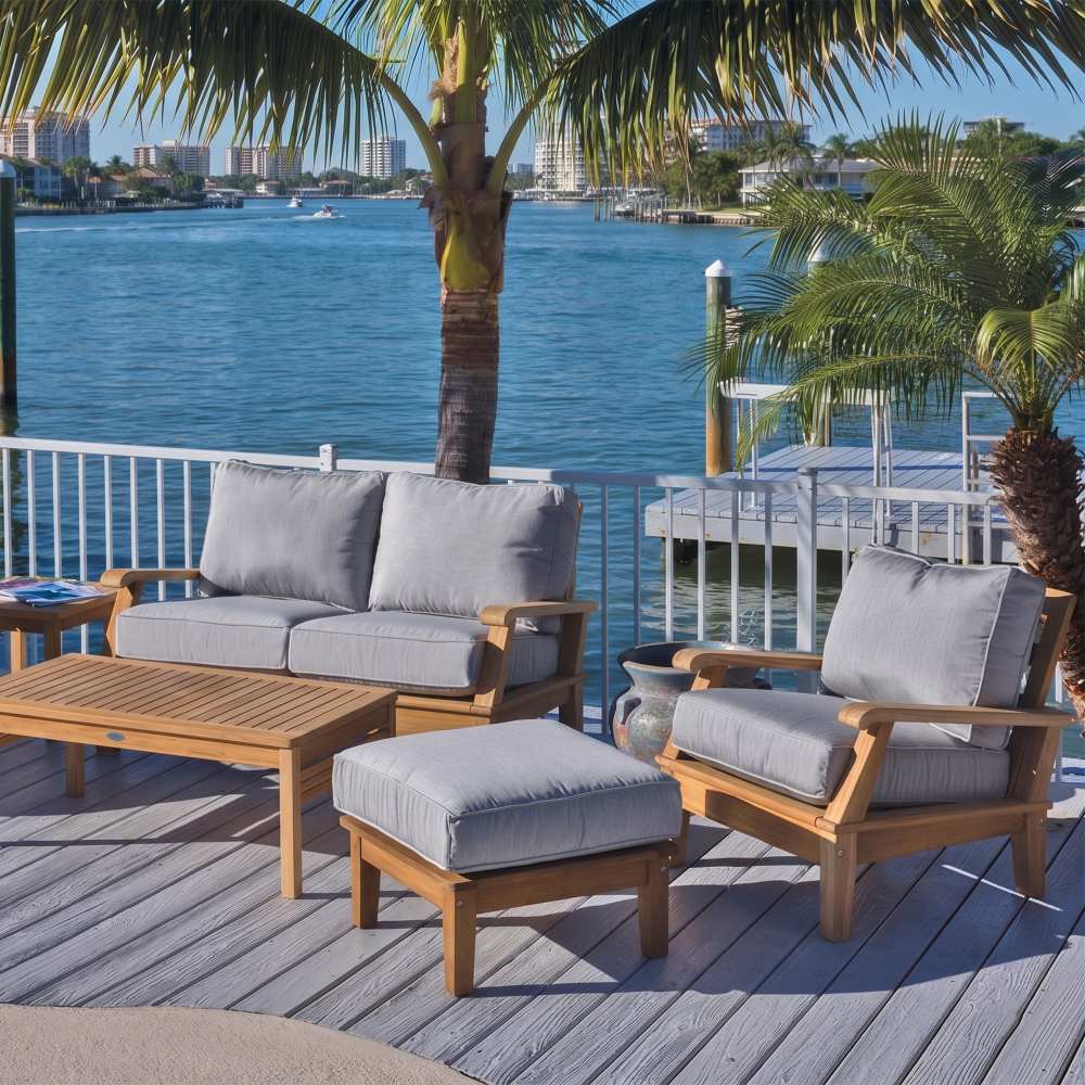 Teak outdoor lounge set with light-gray cushions, ottoman, and coffee table