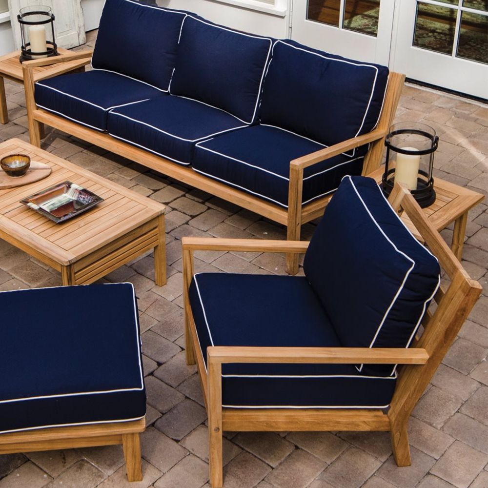 Teak outdoor ottoman with dark navy cushion and white trim piping on frame