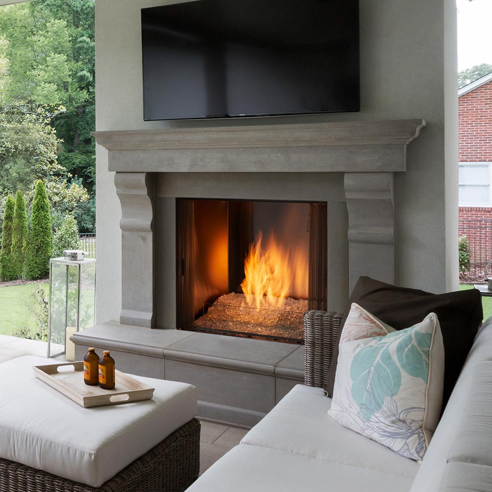 Outdoor gas fireplace with burning flames, tan fire glass, and grey stone surround