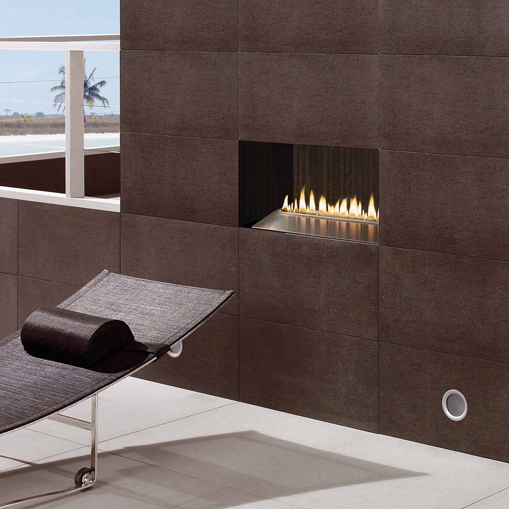 Wall-mounted linear gas burner with flames and dark metal surround