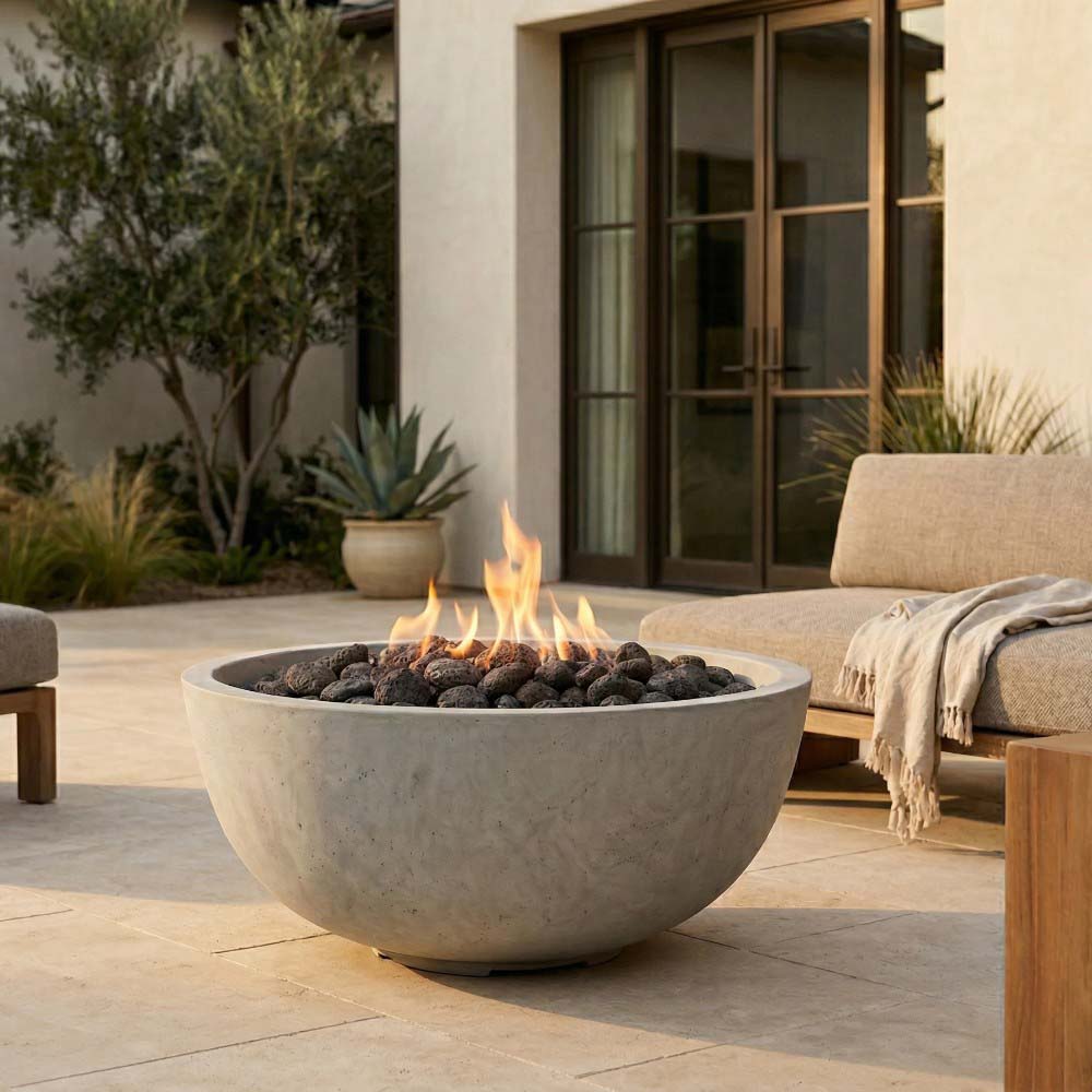 Tan concrete gas fire pit bowl with flames, filled with dark lava rocks