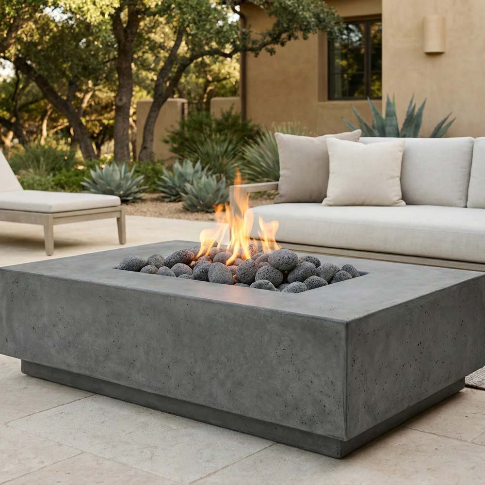 Gray concrete gas fire pit with glowing flames and black lava rocks