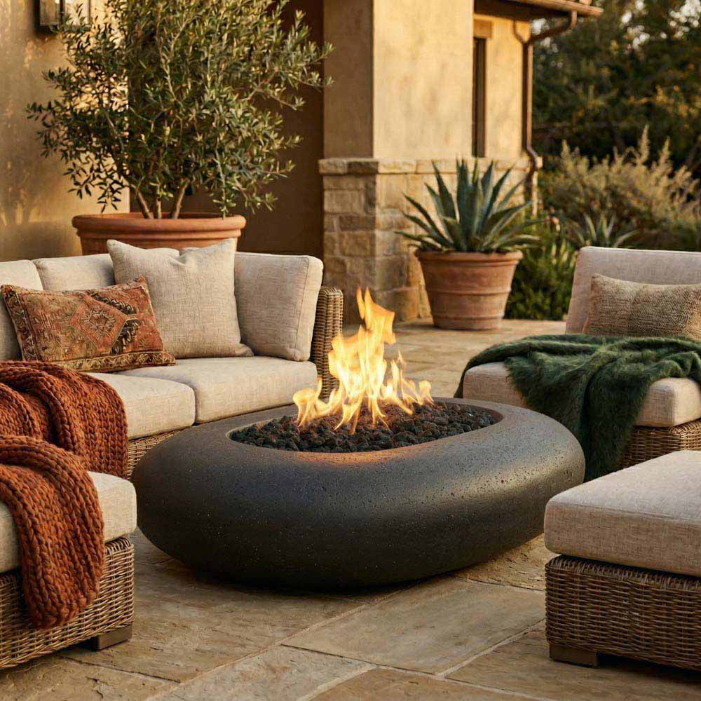 Oval pebble-concrete gas fire pit with flames, dark gray pebble fire bed