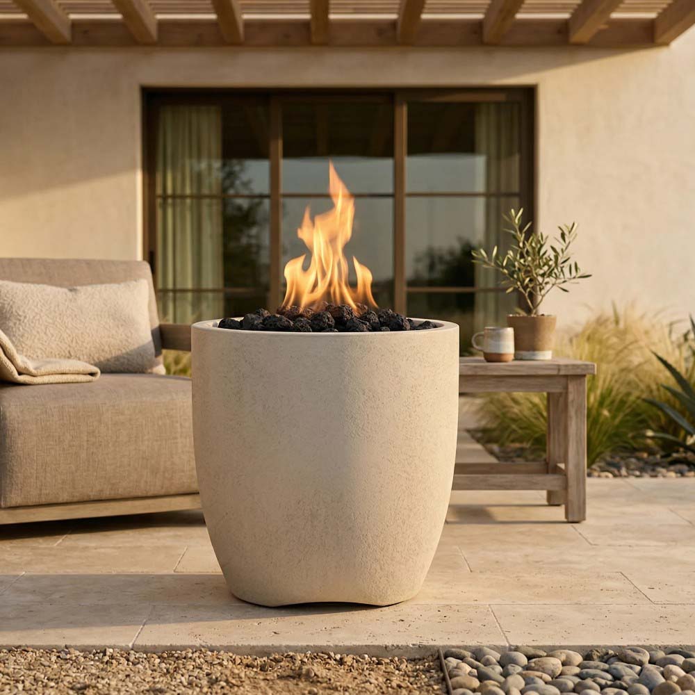 Light concrete gas fire pit bowl with flames rising from dark fire media