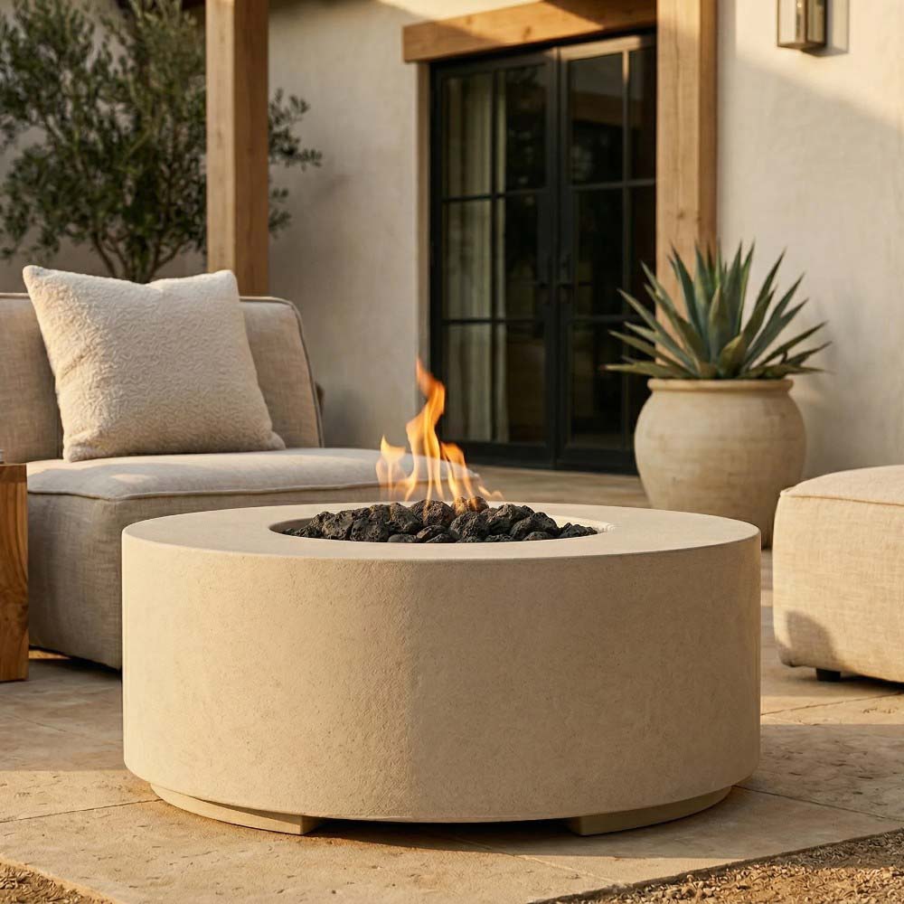 Round concrete gas fire pit in light beige with flame and black lava rocks