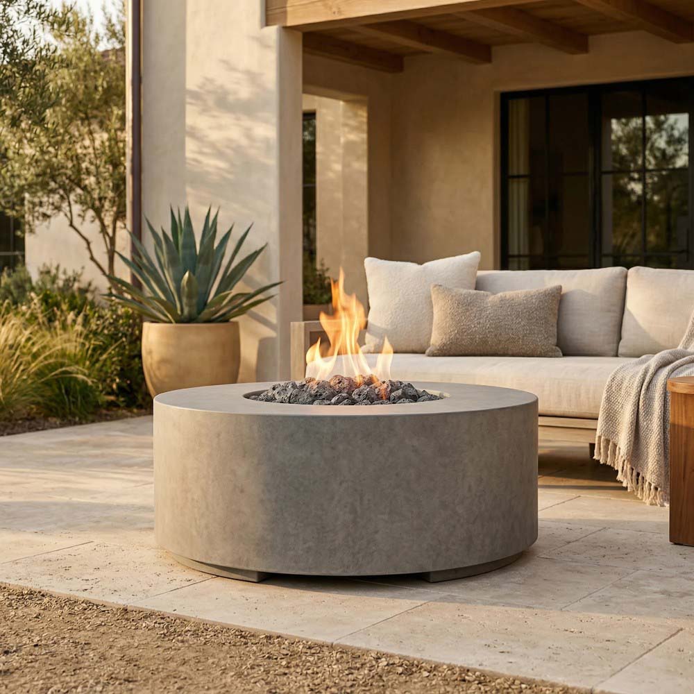 Round concrete gas fire pit in light gray with flame and black lava rocks