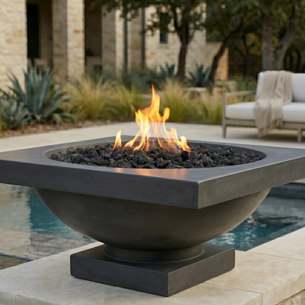 Dark concrete gas fire bowl with lava rocks and active flames outdoors
