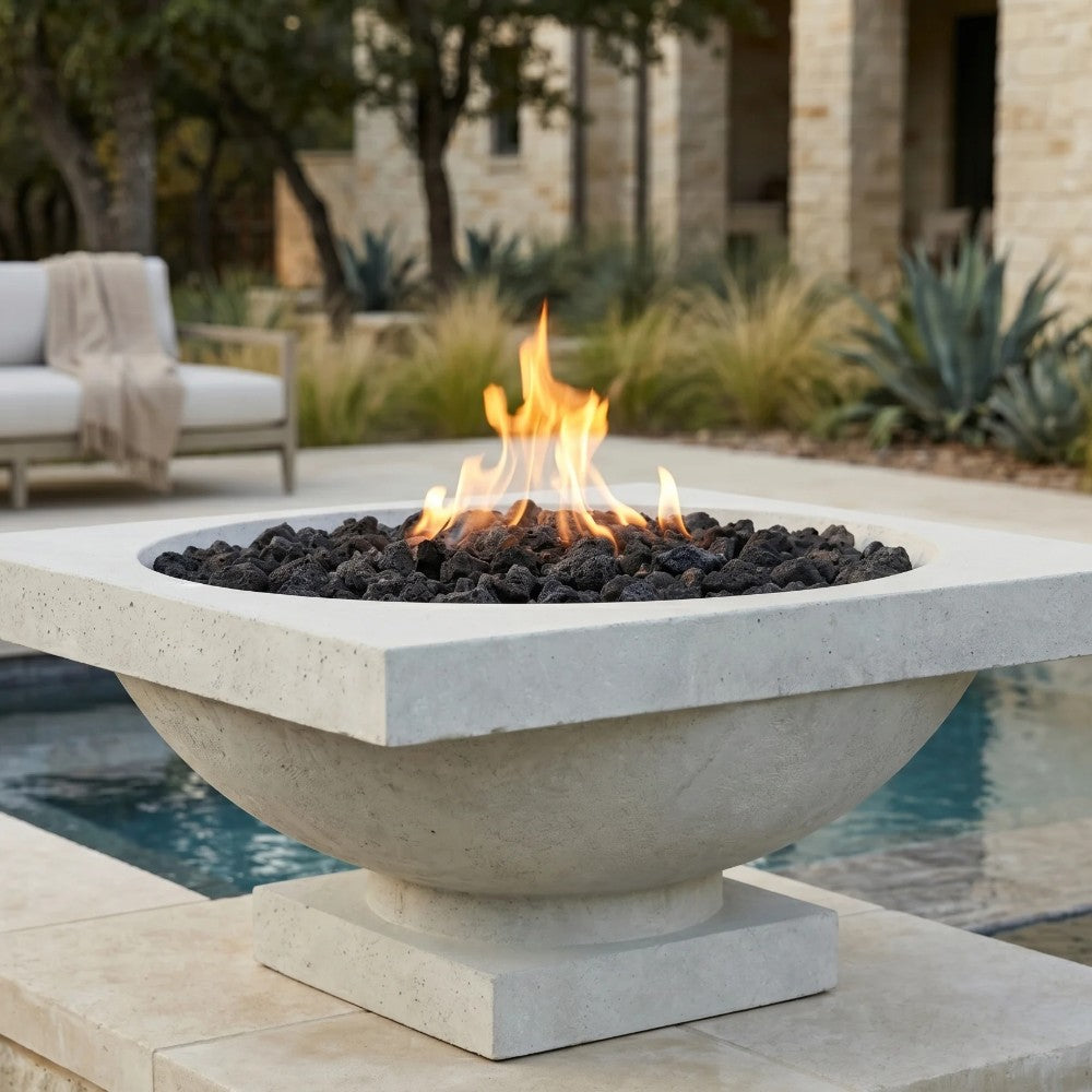 Light concrete gas fire bowl with lava rocks and flames on patio