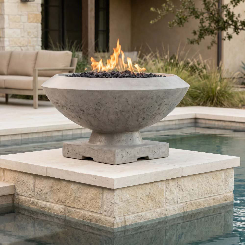 Gray concrete gas fire bowl with flame rising from lava rock, on a raised stone stand