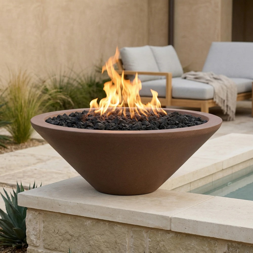 Concrete pedestal gas fire pit in warm tan with flames and black lava rocks