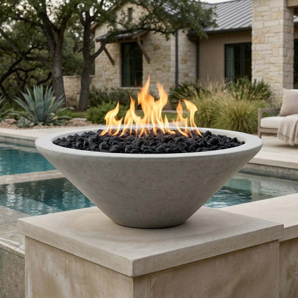 Concrete pedestal gas fire pit in white tone with flames and black lava rocks