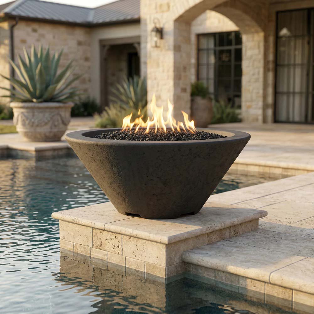 Tan concrete gas fire bowl with flames on black burner bed, on stone base.