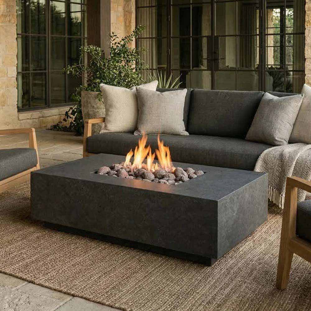 Outdoor rectangular concrete gas fire pit with burning flames and dark burner area