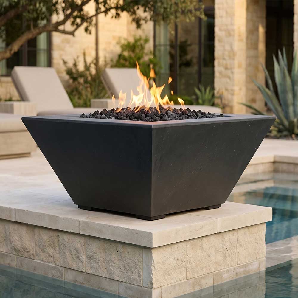 Tall concrete gas fire pit with dark finish, open flame visible above lava rocks