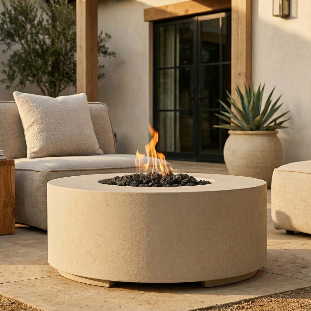 Round concrete gas fire pit with flames and black lava rocks, light concrete finish