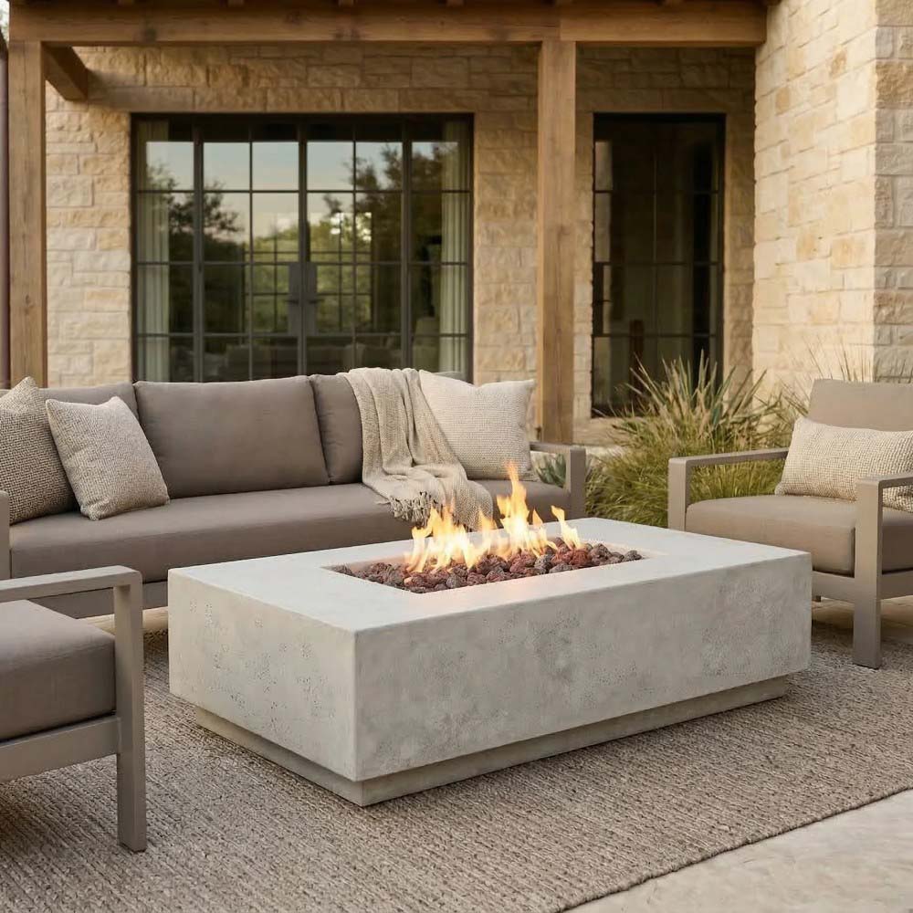 Light concrete rectangular gas fire pit with flames in front of outdoor seating