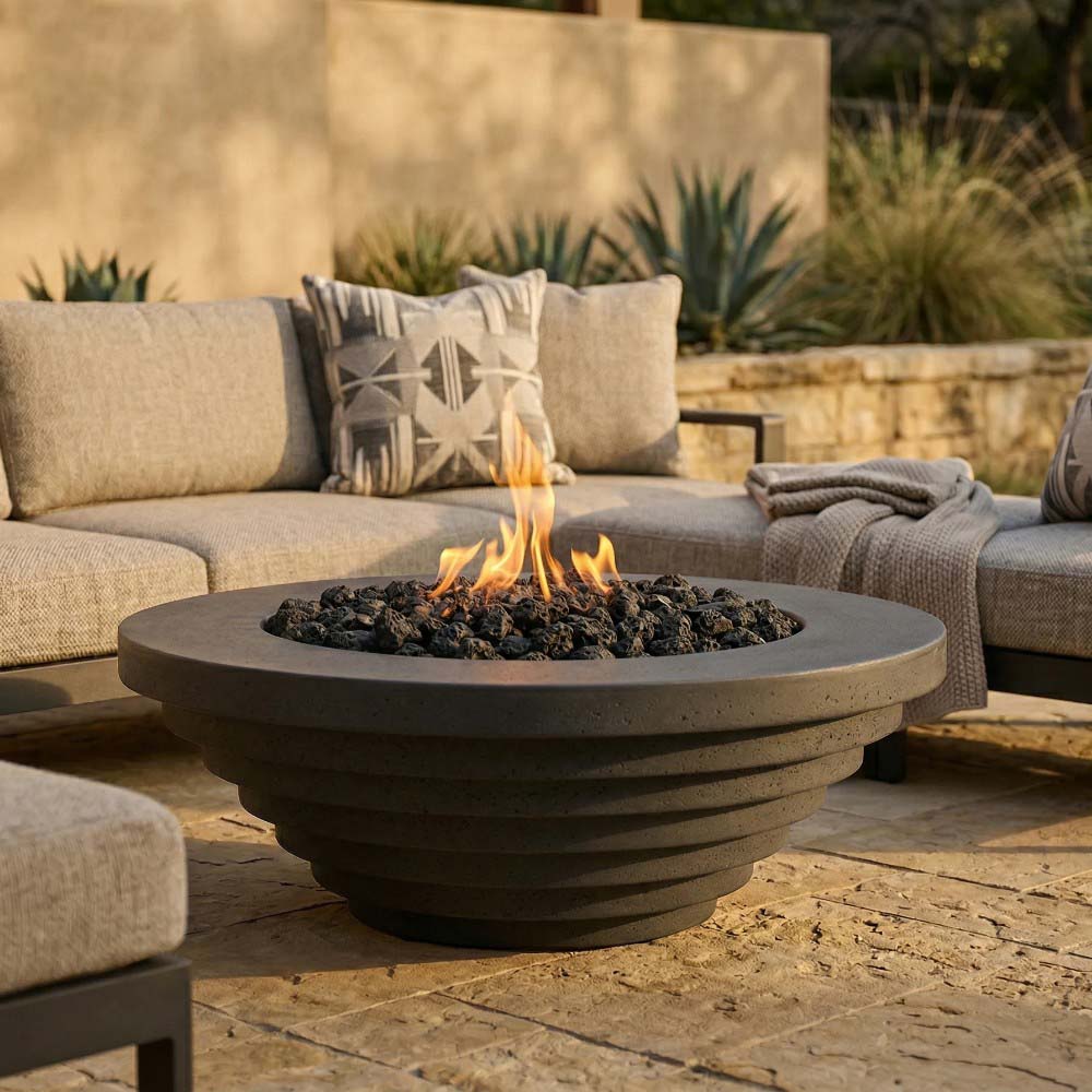 Concrete gas fire pit on patio with open flame in center bowl