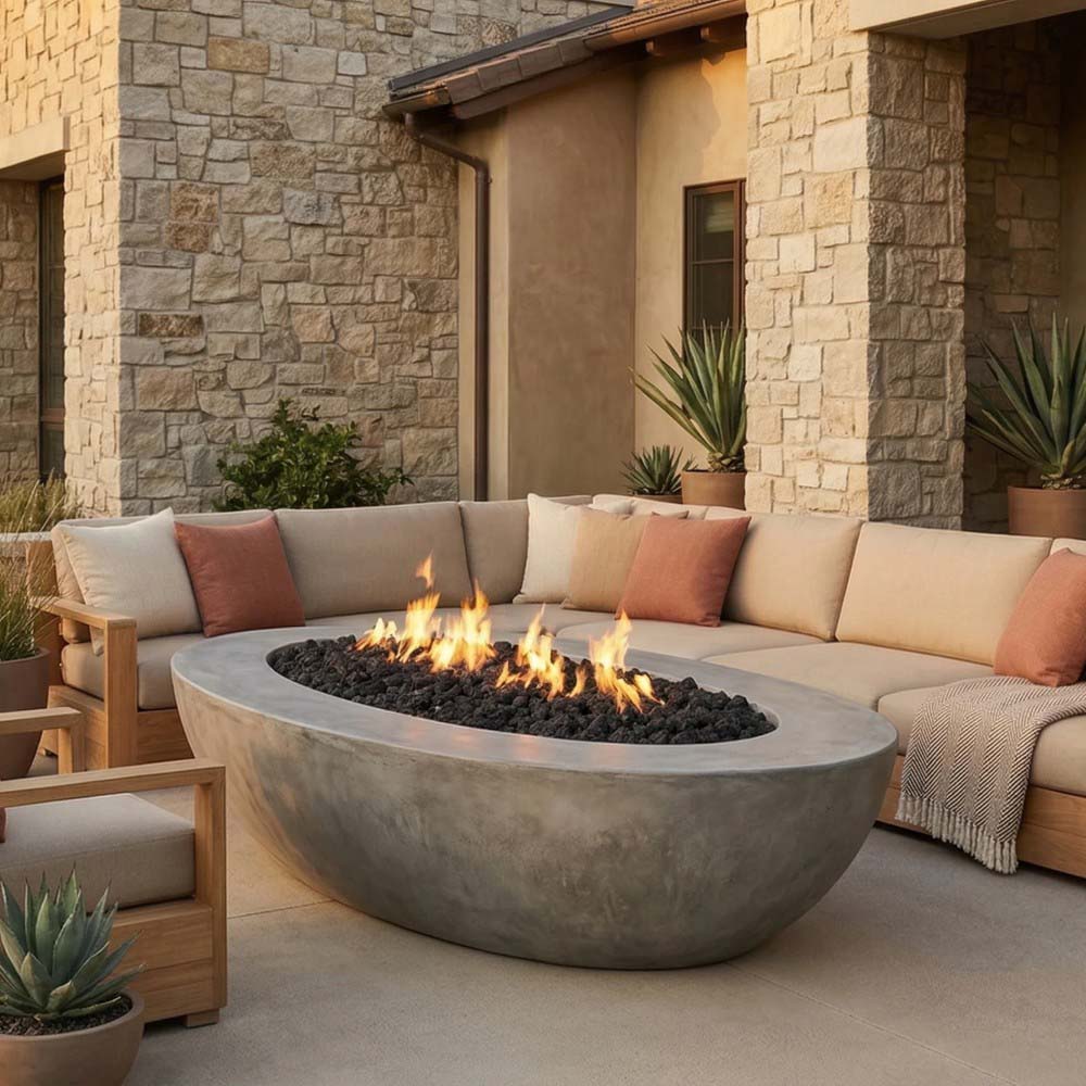 Oval concrete gas fire pit with lit flames and charcoal-gray outer bowl