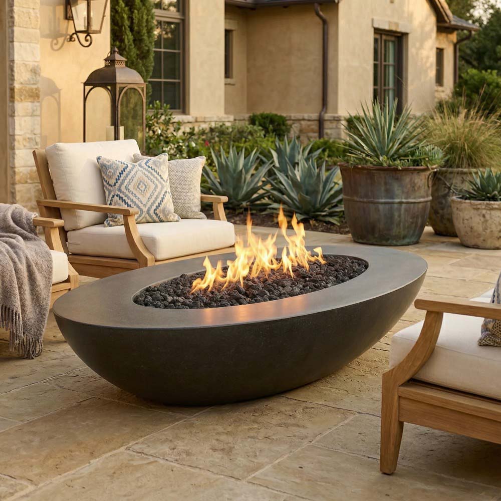 Oval concrete gas fire pit with lit burner bowl and dark gray body