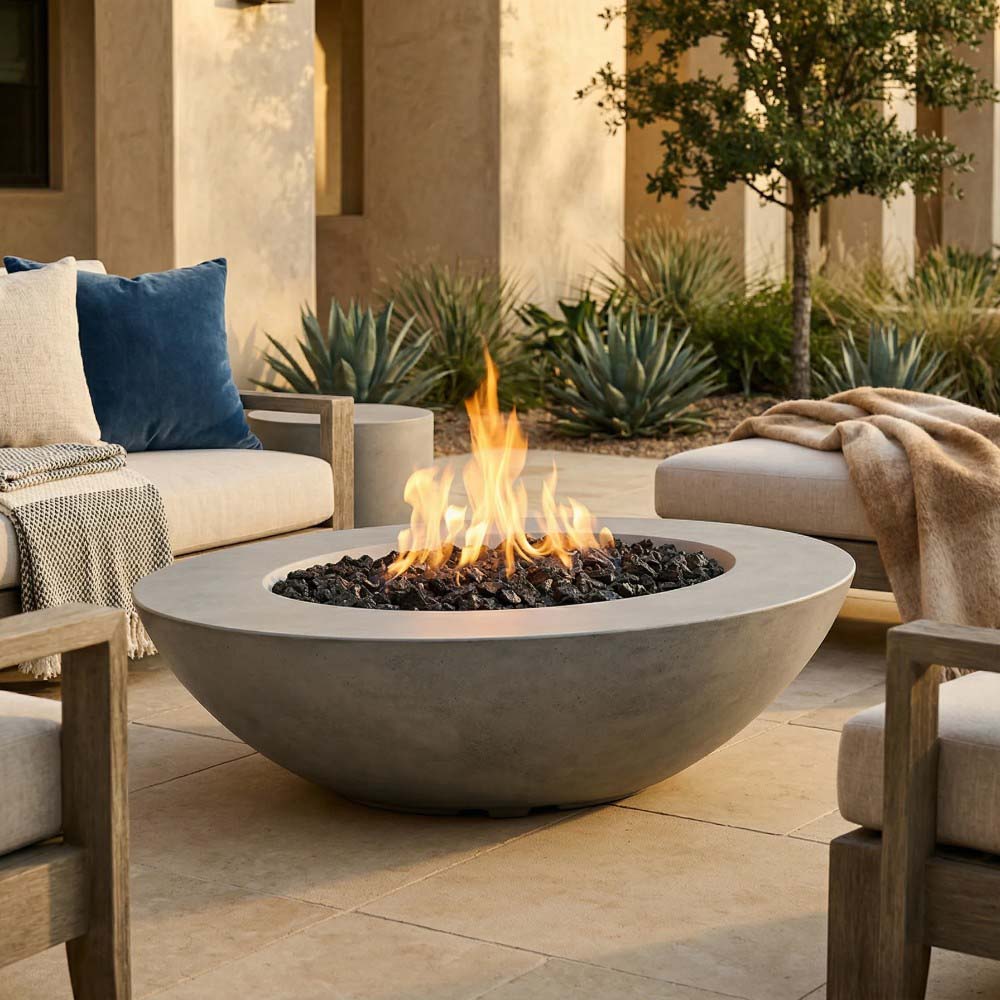 Grey oval concrete gas fire pit with active flames over the black burner insert
