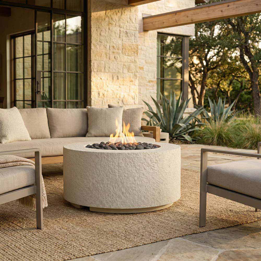 Cylindrical concrete gas fire pit with flame and burner rocks on patio