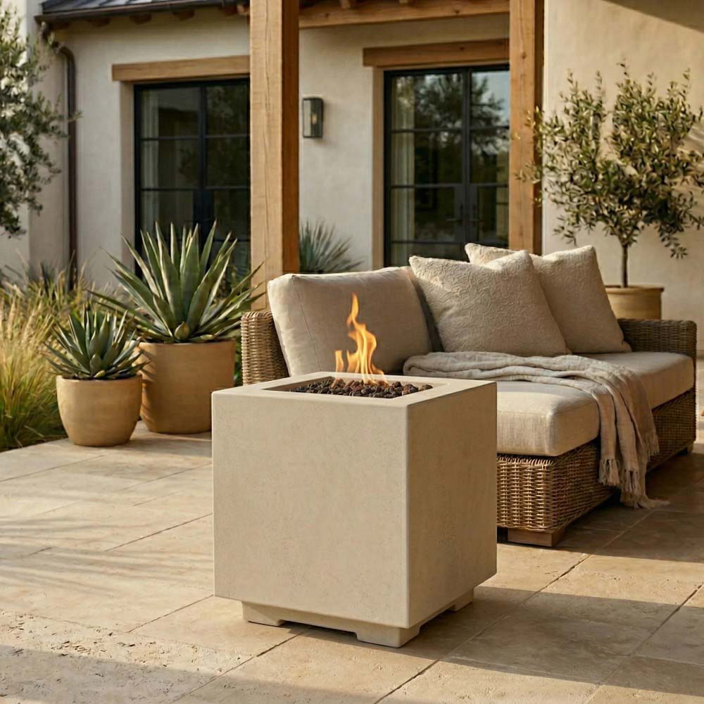 Light beige square concrete gas fire pit with flames burning in the bowl.