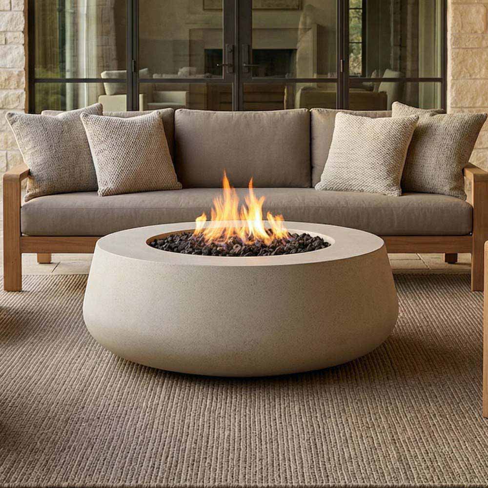 Light gray concrete gas fire bowl with centered flame over black lava rock bed