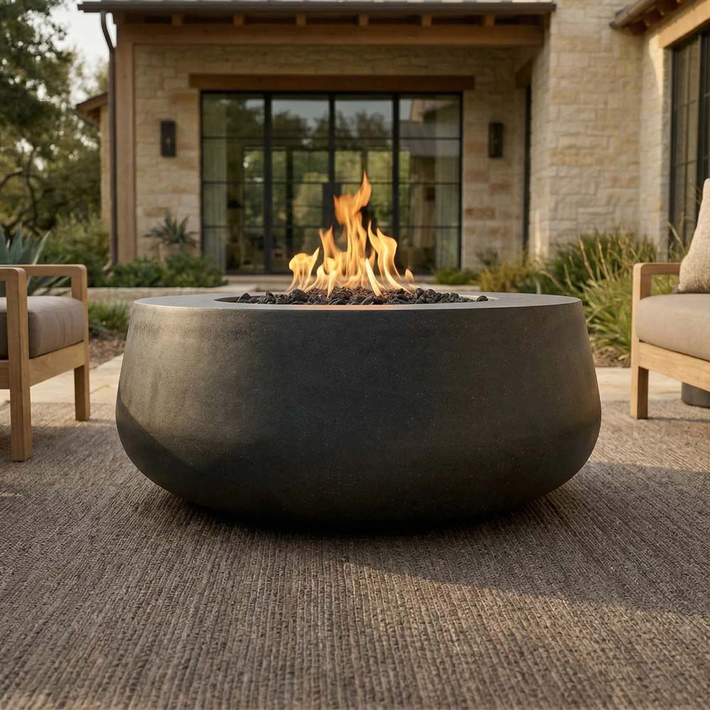 Dark gray concrete gas fire bowl with tall flames burning over lava rock bed