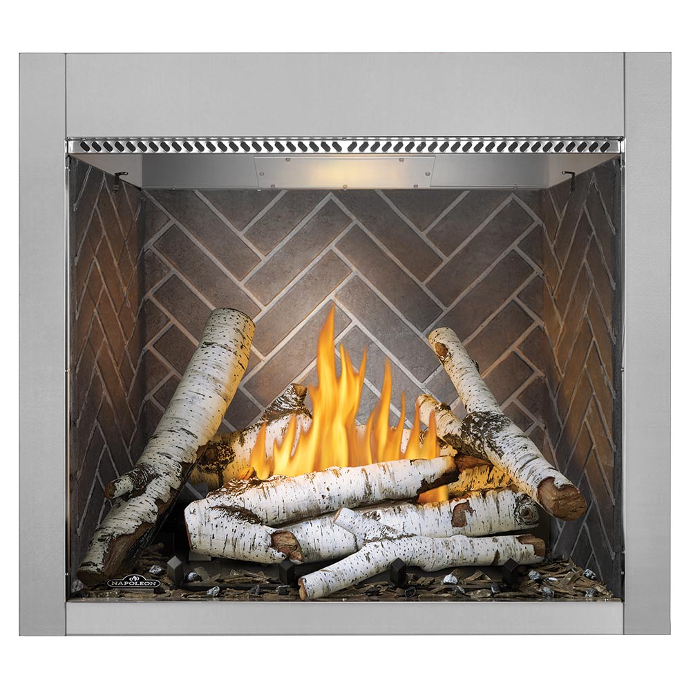 Outdoor gas fireplace with burning birch logs and gray herringbone brick back panel