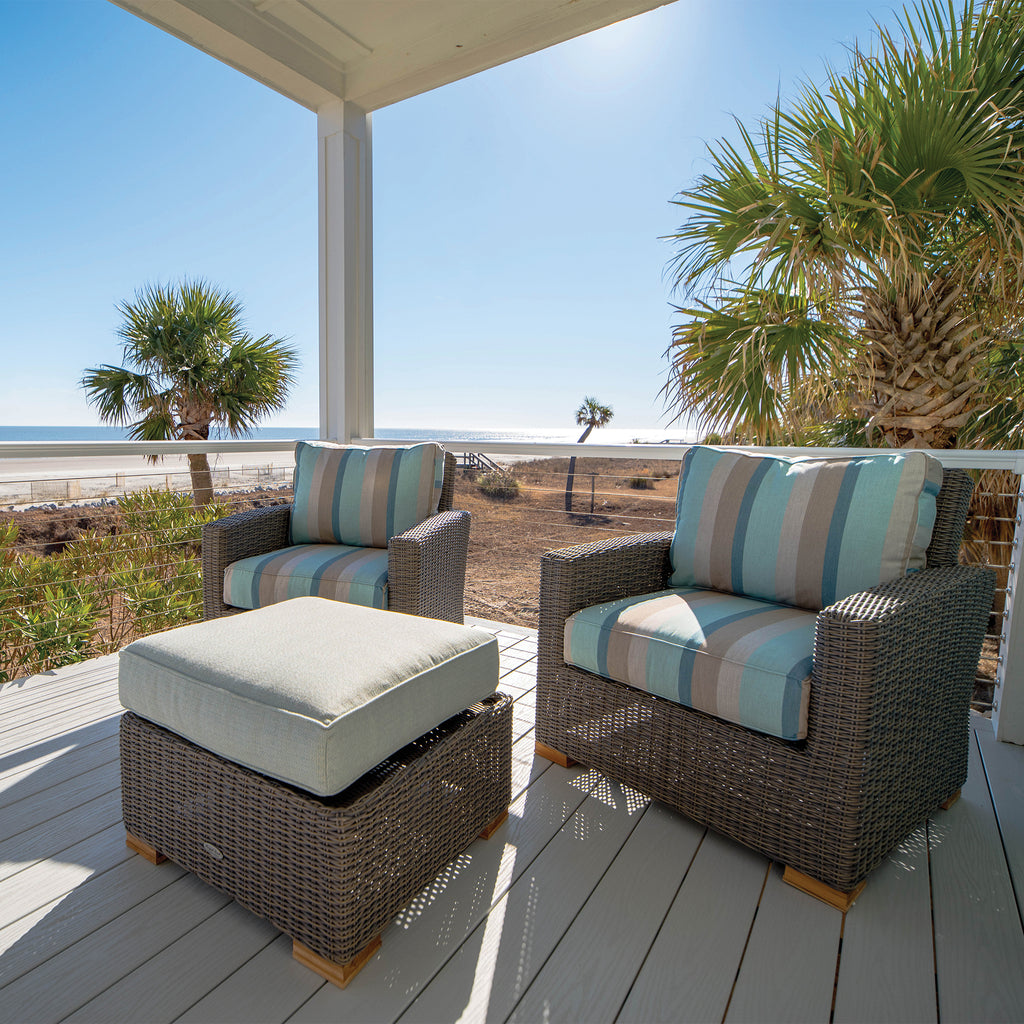 Outdoor seating set with dark wicker armchairs, striped cushions, and a matching ottoman